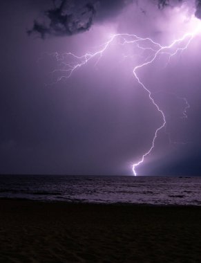 Lightning storm at night over the ocean clipart