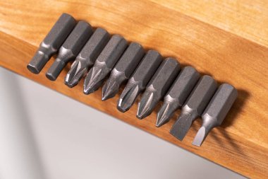 Katı ahşap tezgahın kenarında birkaç farklı tornavida ucu var. Yukarıdan yaklaş.