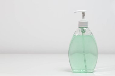 Beyaz arkaplanda bir şişe el dezenfektanı ve sol tarafta kopya alanı var..