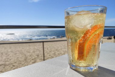 Yazın plajda serinletici soğuk içecekler. Buzlu ve portakal dilimli gazlı zencefilli bira..