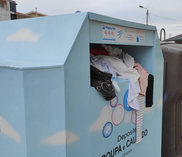 Clothing left in recycling bin for fabrics and clothes in rural Portugal