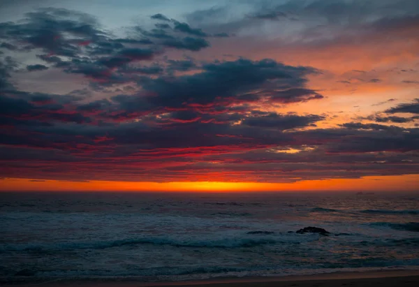Dramatic, vivid sunset sky over the ocean at dusk. Bright red and orange colors