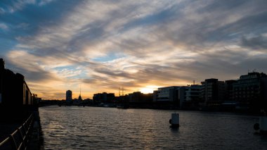 Dublin, İrlanda siluet şehri. Gün batımında Liffey nehrinin üzerinde, karamsar bulutlarla.