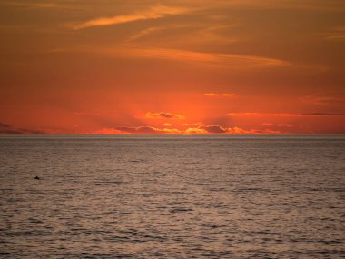 Portekiz 'de okyanusun üzerinde gün batımında canlı renkli bir gökyüzü. Güneş ufkun altında.