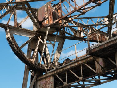 Kullanılmayan iskelede eski, paslı, yıpranmış bir vinç. Mavi gökyüzüne karşı aşağıdan ateş edilmiş. Dublin rıhtımı.