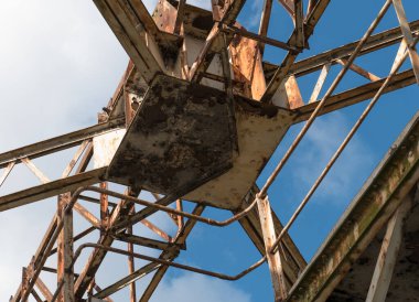 Eski, paslı, yıpranmış yükleme vinci terk edilmiş kargo iskelesinde. Mavi gökyüzüne karşı aşağıdan ateş edilmiş. Dublin rıhtımı.