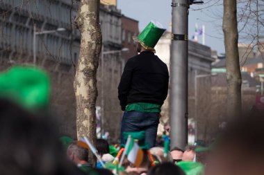 Yeşil şapkalı tanımlanamayan adam Aziz Patrick Günü geçit töreni için Dublin 'deki O' Connell Sokağı 'nda kalabalığın üzerinde duruyor..