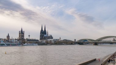 Gündüz vakti Köln Katedrali ve Hohenzollern Köprüsü 'nü gösteren Ren Nehri' ne bakın. Ren 'in genişliğini vurgulayan geniş açı çekimi.