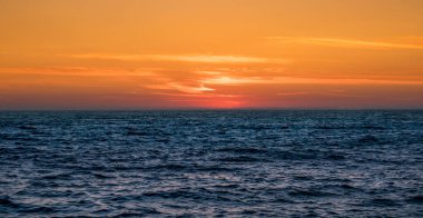 Güneş, gün batımında, Portekiz 'in Atlantik Okyanusu üzerinde ufkun üzerinde kayboluyor. Canlı turuncu gökyüzü.