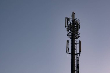 Cep telefonu kulesi / iletişim anteni ya da karanlık mavi gökyüzüne karşı alacakaranlıkta silüet halinde. Boşluğu sola kopyala.