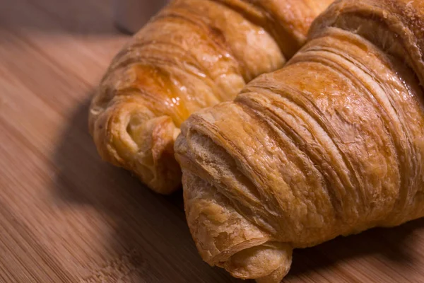 Two French breakfast croissants on a natural wooden background. Closeup.