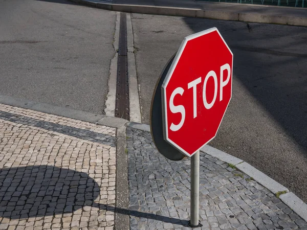 Stop sign in Portuguese street with typical cobblestones sidewalk.