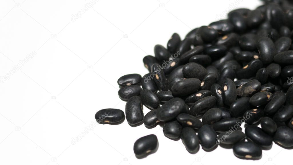 Heap of raw black beans on white background with space on left