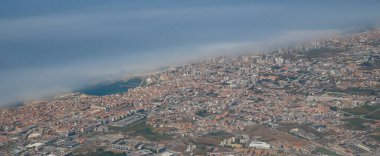 Portekiz 'de Vila do Conde ve Povoa de Varzim' in Atlantik kıyısında kalın bulutlu bir uçaktan çekilmiş yüksek irtifa görüntüsü.
