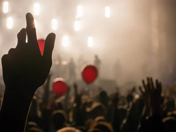 Hand in the air during rock concert silhouetted against bright lights from stage. Shallow depth of field