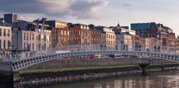 Dublin, İrlanda 'daki Liffey Nehri' nde yarım peni köprüsü ve alacakaranlıkta nehir kenarındaki binalar.
