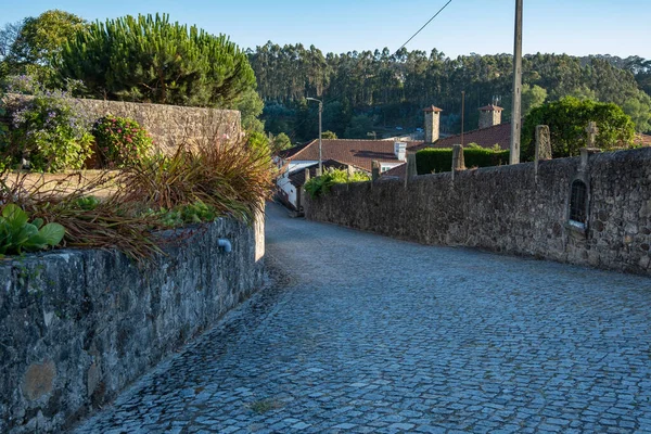 夏のポルトガルの農村部の石畳の通りと地平線の古い石の壁と木 — ストック写真