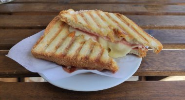 Ahşap bir masada kızarmış jambonlu ve peynirli sandviç. Basit bir atıştırmalık ya da erimiş peynir, jambon ve ekmek ile öğle yemeği..