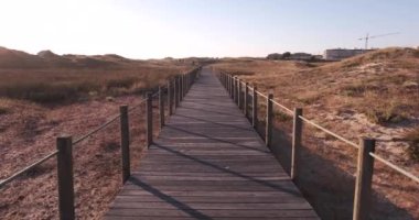Portekiz 'in Vila do Conde bölgesindeki kum tepelerinin üzerinde tahta tahta kaldırım. İleri doğru yürü, birinci şahıs POV.