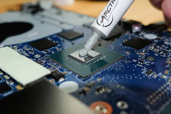 Bilgisayar anakartında Nvidia GPU 'ya termal yapıştırıcı uygulayan teknisyen..
