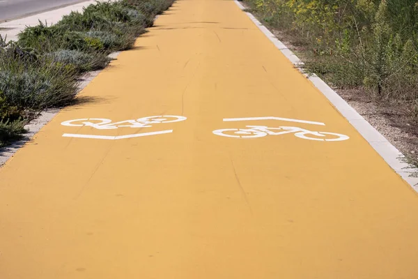 Yellow cycle lane with white painted bicycle symbols. Low angle perspective view.