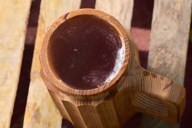 Olgun sulu yaz bir arka plan üzerinde ahşap bir kupa bira