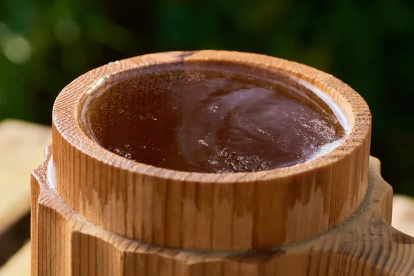 Olgun sulu yaz bir arka plan üzerinde ahşap bir kupa bira