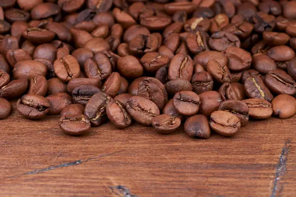 Granos de café sobre un fondo de madera dispersos — Foto de Stock