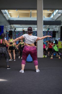Şişko kız Fitness salonunda sınıfında yapıyor: egzersiz müzik ile.
