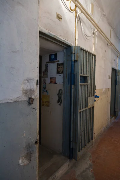 进入一个黑暗的房间的监狱牢房与挂在报纸剪报上的墙上 — 图库照片