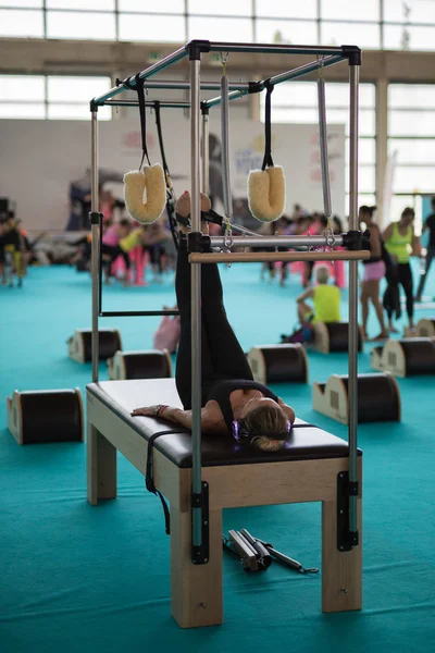 Rimini, İtalya - Haziran 2018: kulaklık yalan bacaklar çekiş eğitim donanımları vasıl jimnastik salonu ile egzersizleri yapıyor yatakta kızla.