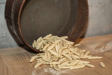 Kısa, pişmemiş makarna dairesel bir bakır kap dışarı geliyor.