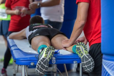 Fiziksel bir spor egzersiz yaptıktan sonra bacaklar masaj yaparken bir yatakta yatarken atlet.