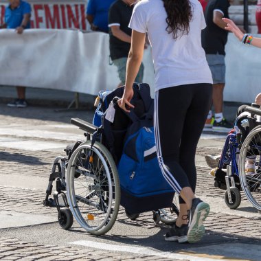 Bir sırt çantası ile bir tekerlekli sandalye üzerinde maratonunu sırasında iterek kız