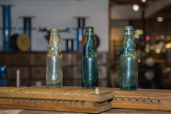 Trois bouteilles en verre vertes, vides et sales sur un panneau en bois — Photo