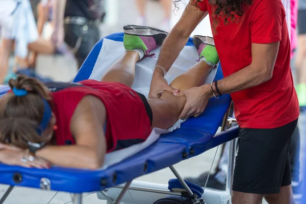 Atleta sdraiato su un letto mentre ha le gambe massaggiate dopo un allenamento di sport fisici — Foto Stock
