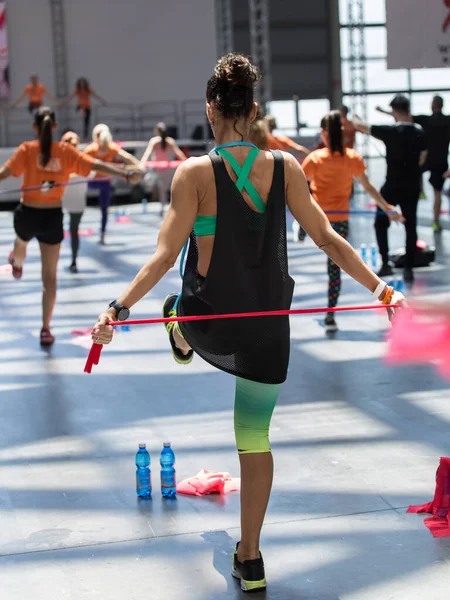 Rimini, Olaszország-május 2019: emberek gyakorlása a fitness rugalmas Band osztályban a tornaterem zenével és tanár a színpadon. — Stock Fotó