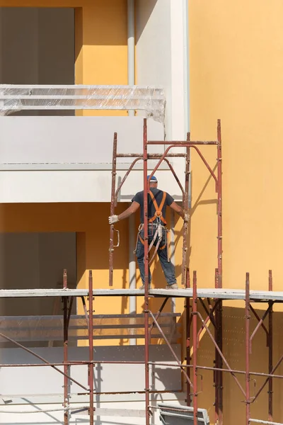为建造建筑物而在建筑工地上工作时戴蓝色硬礼帽的工人 — 图库照片