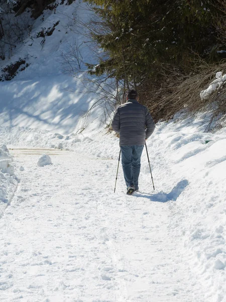 在雪道上行走的老人的后视镜 在冰雹的支持下 — 图库照片