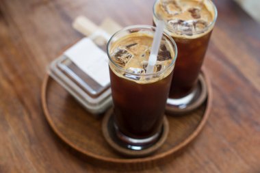 İki buzlu kahve ve cam bardaklar bir kafede ahşap tepside.