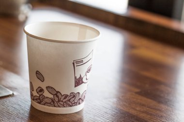 Tahta masanın üzerinde bir fincan kağıt kahve.