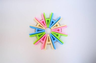 Beyaz arkaplanda daire şeklinde renkli mandallar