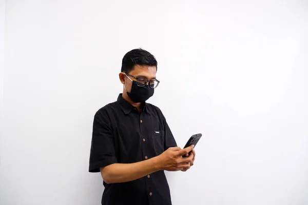 Maskeli genç bir Asyalı telefonuyla mesaj yazıyor.