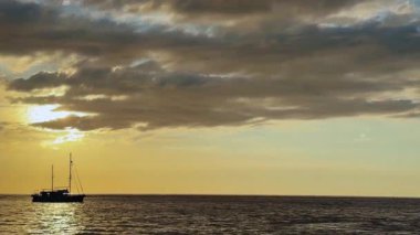 Turuncu gün batımında yelkenli denizde süzülür.