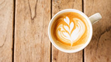 Tahta bir masada sıcak latte kahve..