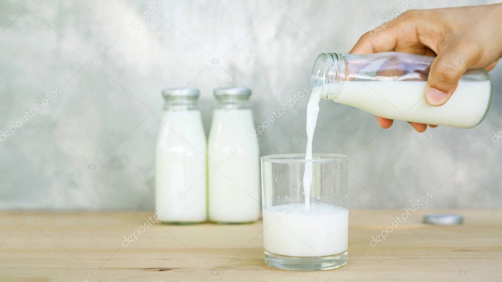 man pouring a milk on a wooden table.