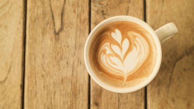 Ahşap bir masada sıcak latte kahve, antika renk..