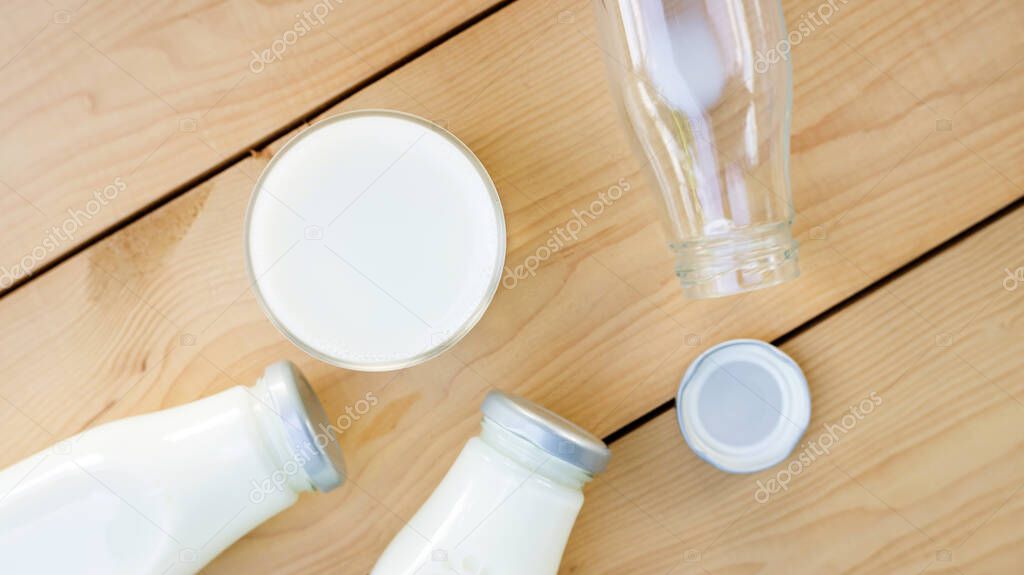 a bottle and glass of milk on a wooden table.