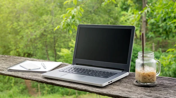 Laptop ve buzlu latte, ahşap bir masada..