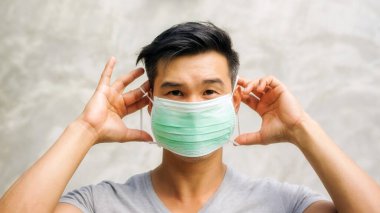 Asyalı adam koruyucu maske takıyor..